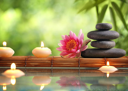 Massagegutschein mit Lotusblüte, Kerzen und Steintürmchen als Bildmotiv