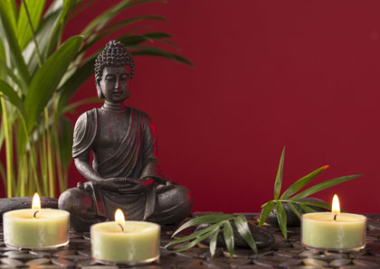 Massagegutschein mit Buddhafigur und brennenden Kerzen als Bildmotiv